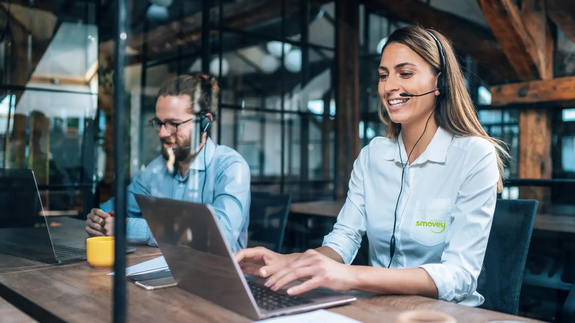 Kundenservicemitarbeiter, die an Laptops arbeiten und Headsets tragen.